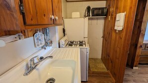 Una cocina compacta con armarios de madera, un fregadero, una estufa y un microondas.
