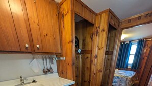 Une cuisine de taille réduite, avec des meubles de rangement en bois, un évier et une petite fenêtre.