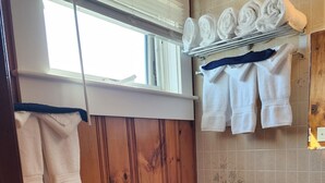 Une salle de bain avec des murs en bois, des toilettes, un lavabo et des serviettes rangées sur un porte-serviettes.