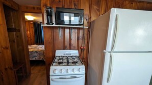 Une cuisine de taille réduite, équipée d’une cuisinière blanche, d’un four à micro-ondes et d’un réfrigérateur.
