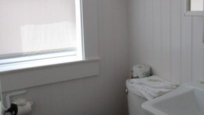 Un baño pequeño con inodoro, lavabo y ventana.