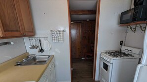 A compact kitchen with wooden cabinets, a sink, a stove, and a microwave.
