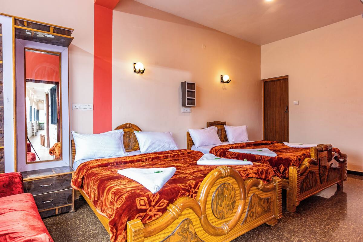 A hotel room with two wooden beds, red and white bedding, a mirror, and wall-mounted lights.