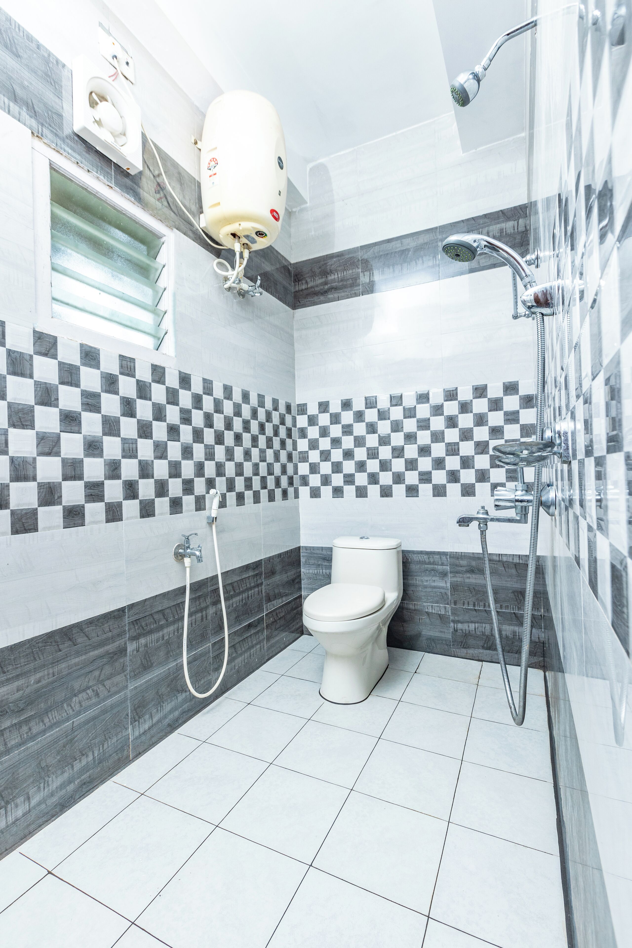 Un baño moderno con inodoro, ducha y salpicadero de azulejos a cuadros.