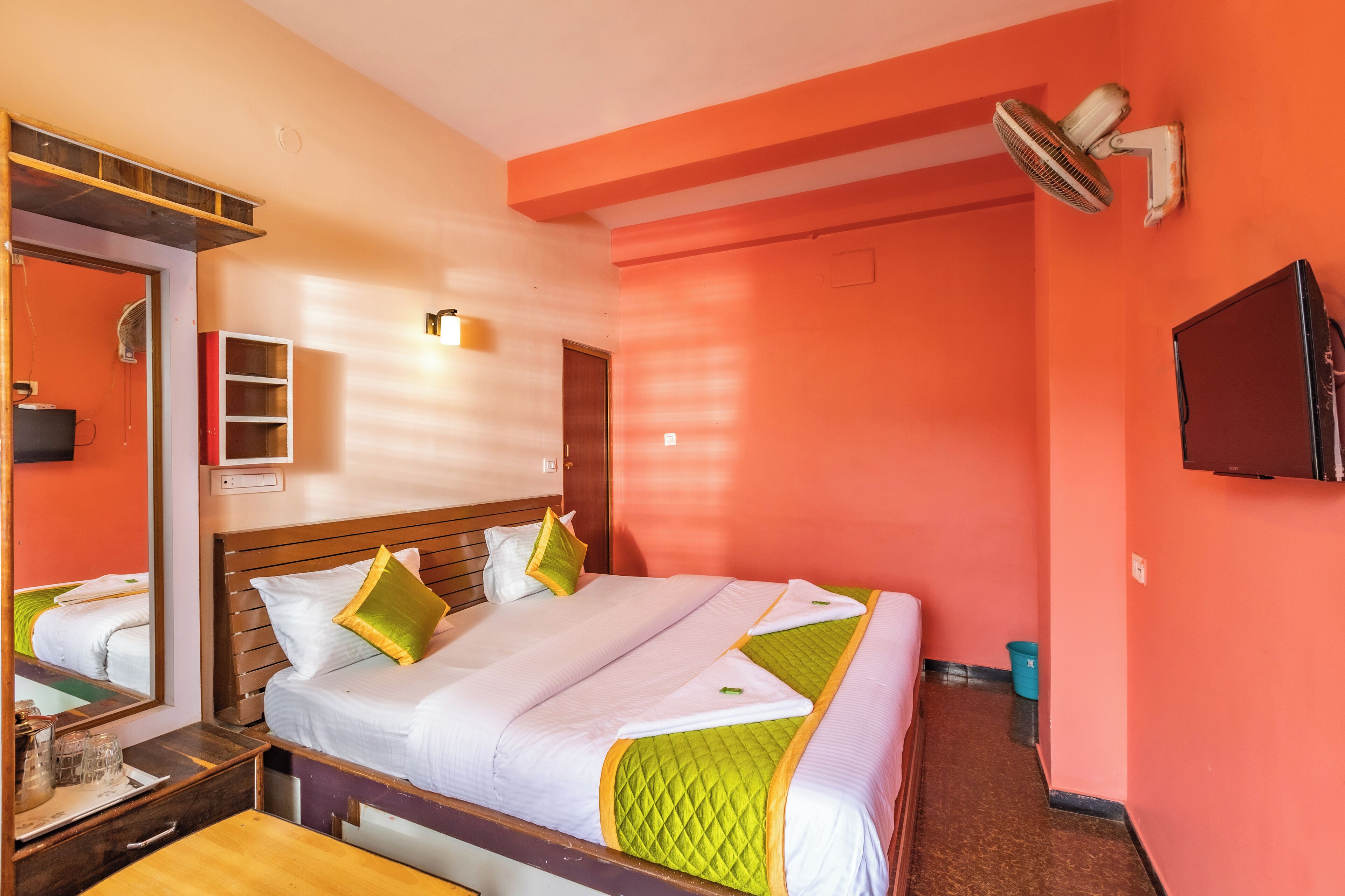 Een hotelkamer met een groot bed, houten hoofdeinde en een spiegel.