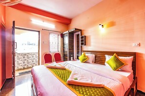 Een hotelkamer met een bed, twee stoelen, een kledingkast en een deur naar buiten.