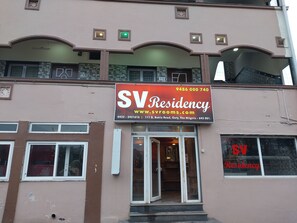 Een gebouw met een bord voor SV Residency, inclusief een website en telefoonnummer.