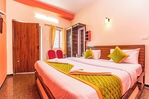 Een hotelkamer met twee bedden, een houten deur, een raam met gordijnen en een wandlamp.