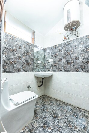 Een badkamer met betegelde vloer, een wit wastafelmeubel en een toilet.
