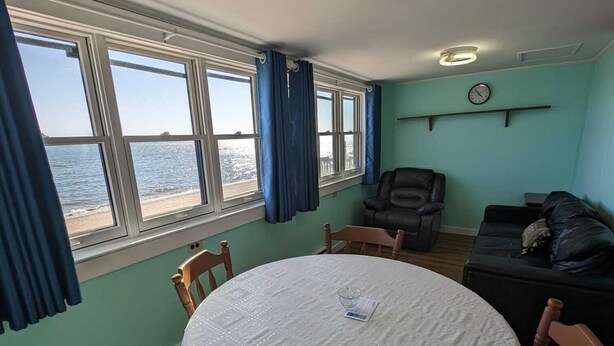 Un comedor con una mesa redonda, sillas y vistas al mar a través de amplios ventanales.