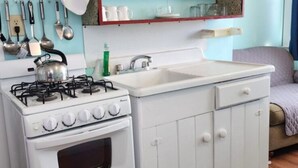 Une cuisine de taille réduite, avec des meubles blancs, une cuisinière, un évier et un four à micro-ondes.