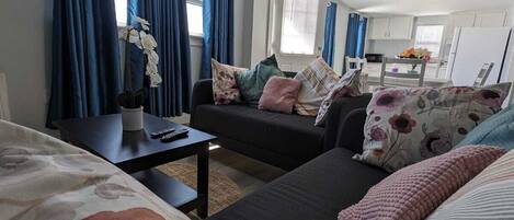 A compact living space with a sofa, a small table, and a bed with floral bedding.
