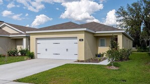 A single-story house with a garage, a well-maintained lawn, and a clear sky.