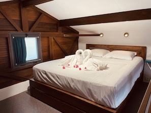 Una cama impecablemente vestida con sábanas blancas y una decoración de toallas con forma de cisne.