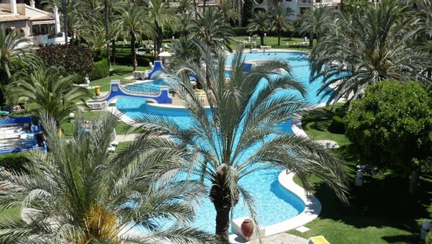 A resort with a large swimming pool surrounded by palm trees and a landscaped garden. - Comfortable spacious family house with large terrace and garden Beach & Bars (Torrevieja)