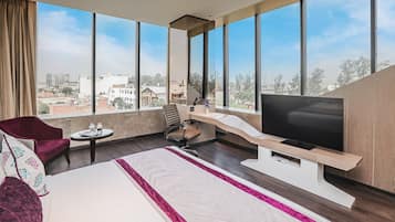 Una habitación de hotel moderna con una cama grande, un televisor, un escritorio y vistas a la ciudad.