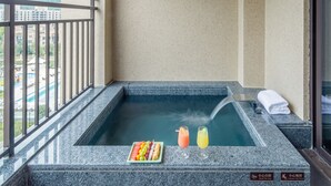 A hot tub with a view of the city, a plate of fruit, and two drinks on a ledge. - Vlamhoo Hotel (Guangzhou)