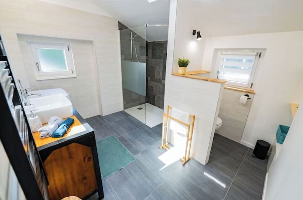 Een moderne badkamer met douche, toilet en wastafel.