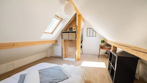 A bedroom with a loft-style ceiling, a bed, a small table, and a desk. - Charming renovated gîte (Rimbach-prés-Guebwiller)