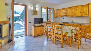 Eine Küche mit Holzausstattung, einem Esstisch mit Stühlen, einem Fernseher und einem Kamin.