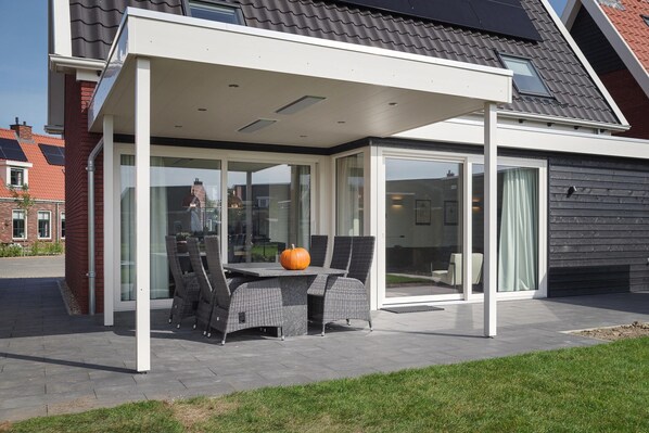 Relax under the sheltered pergola, where a dining table and wicker chairs await.