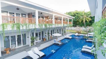 A modern hotel with a rooftop pool area, including lounge chairs and a dining area.