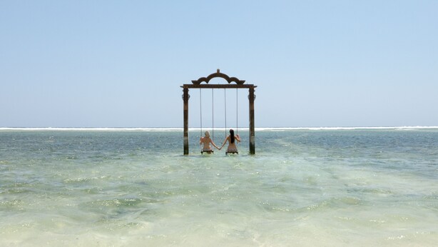 A swing set over a clear ocean. - sea shell resort (Gili Trawangan)
