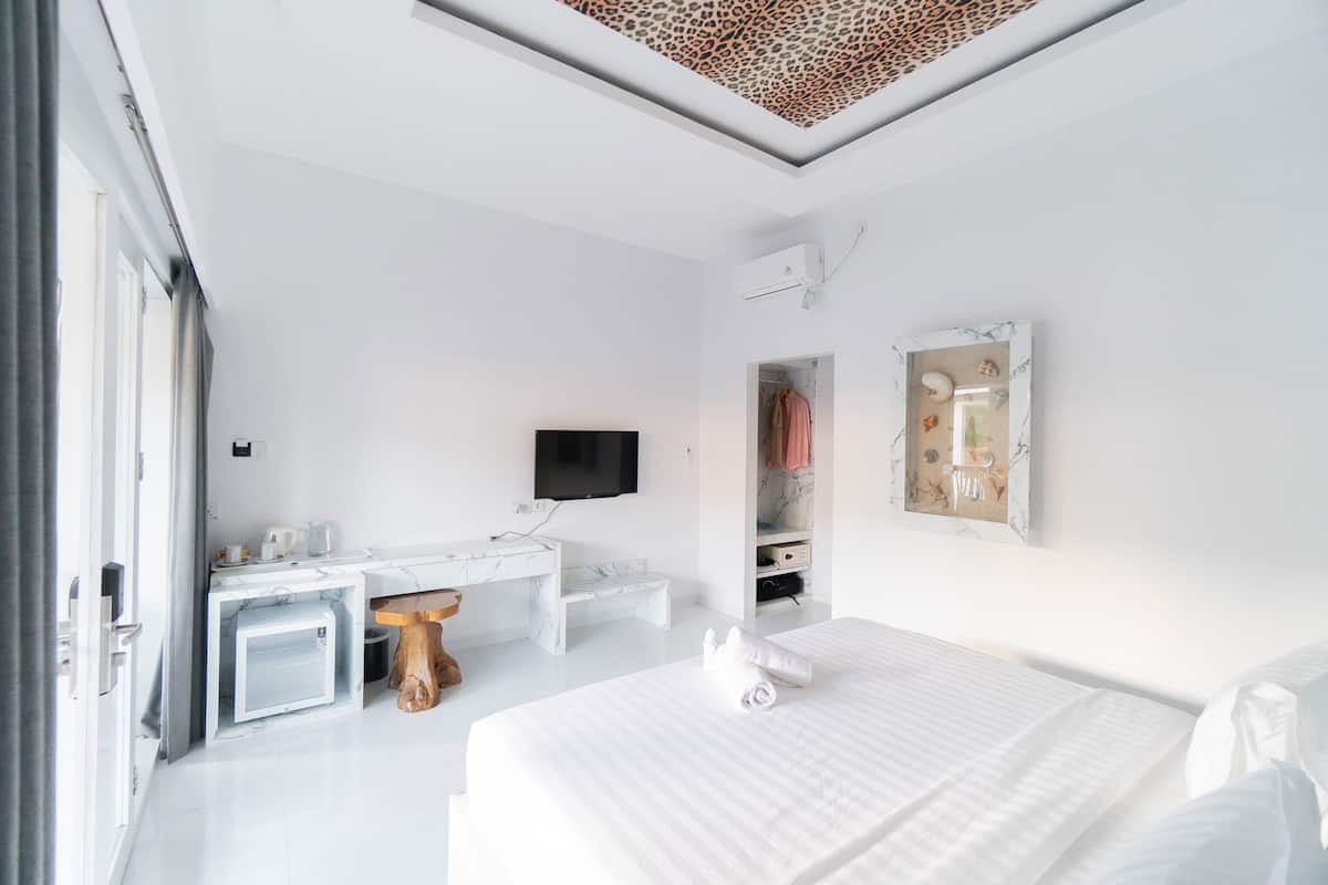 Une chambre d’hôtel moderne équipée d’un grand lit, d’un bureau avec une chaise, d’une télévision et d’une armoire.