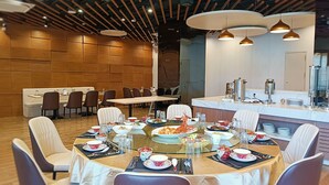 Uma sala de jantar moderna com uma mesa redonda central posta para uma refeição, rodeada por cadeiras.