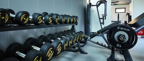 A gym with rows of dumbbells and a weight bench.