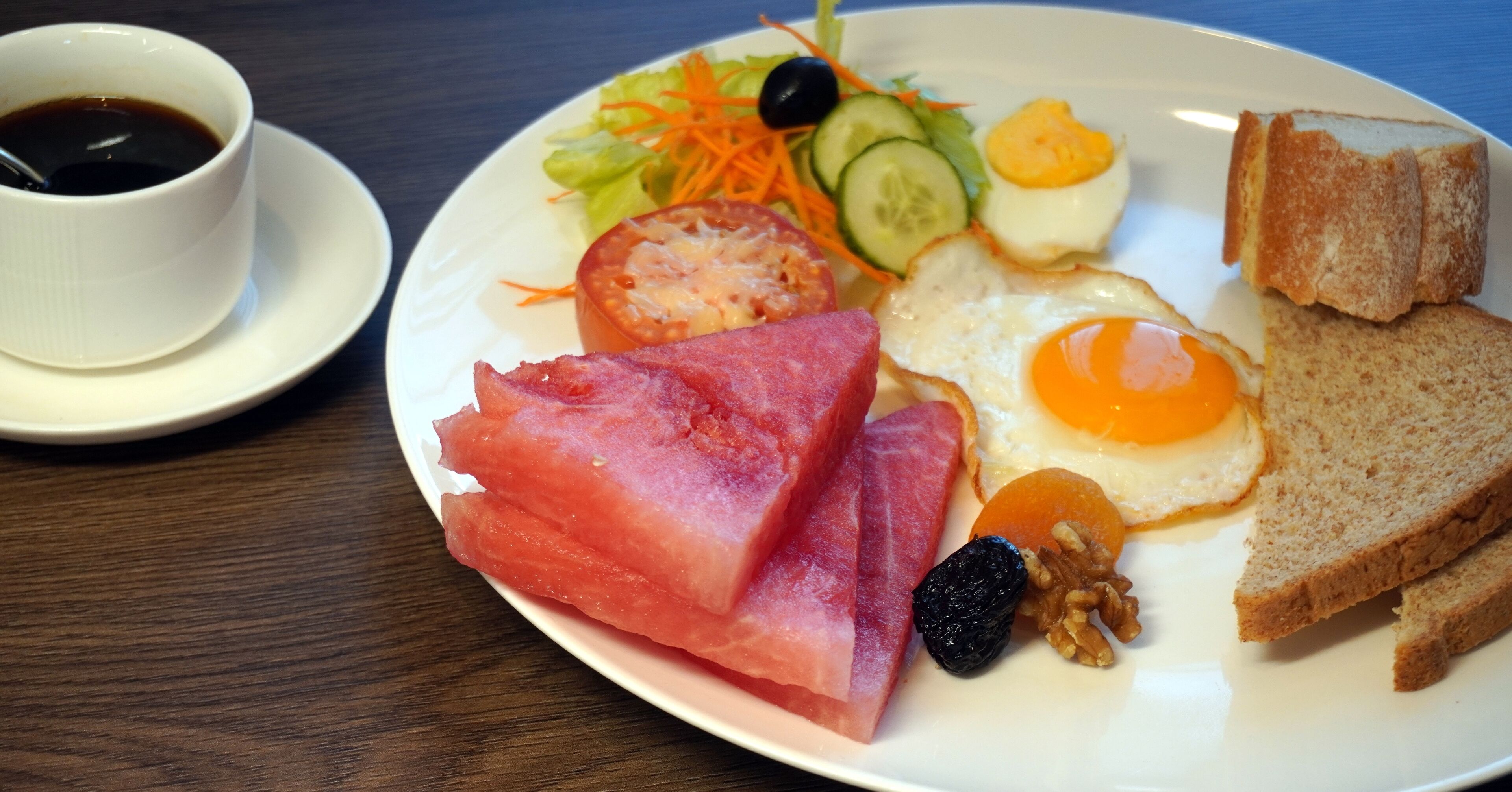 A plate with breakfast items including eggs, bacon, toast, and a cup of coffee.
