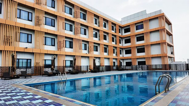 Um hotel moderno com piscina, várias varandas e um espaço de deck revestido com azulejos.