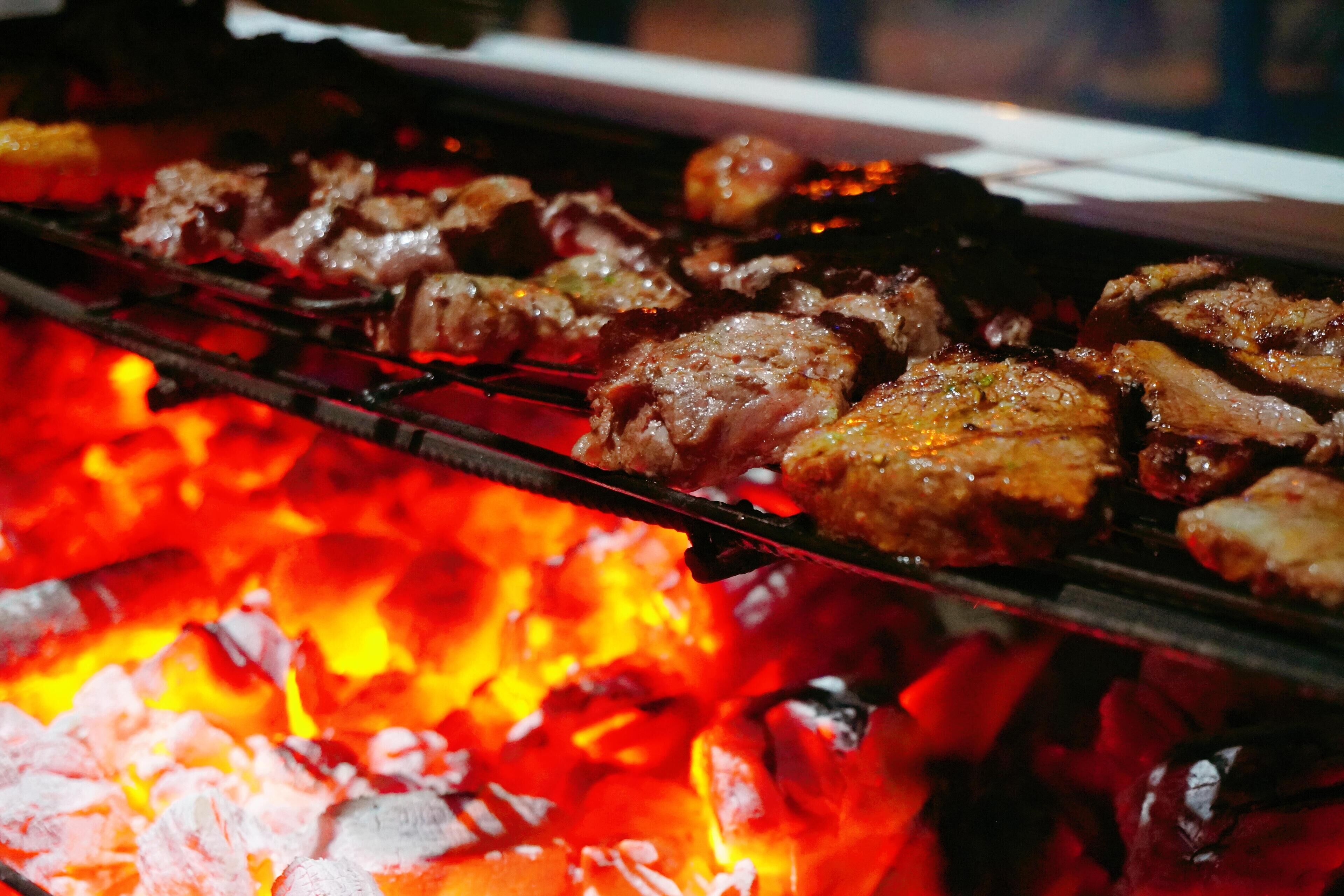 En grill där olika sorters kött tillagas över öppen eld.
