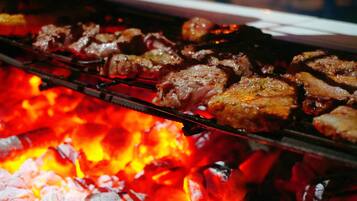 En grill där olika sorters kött tillagas över öppen eld.
