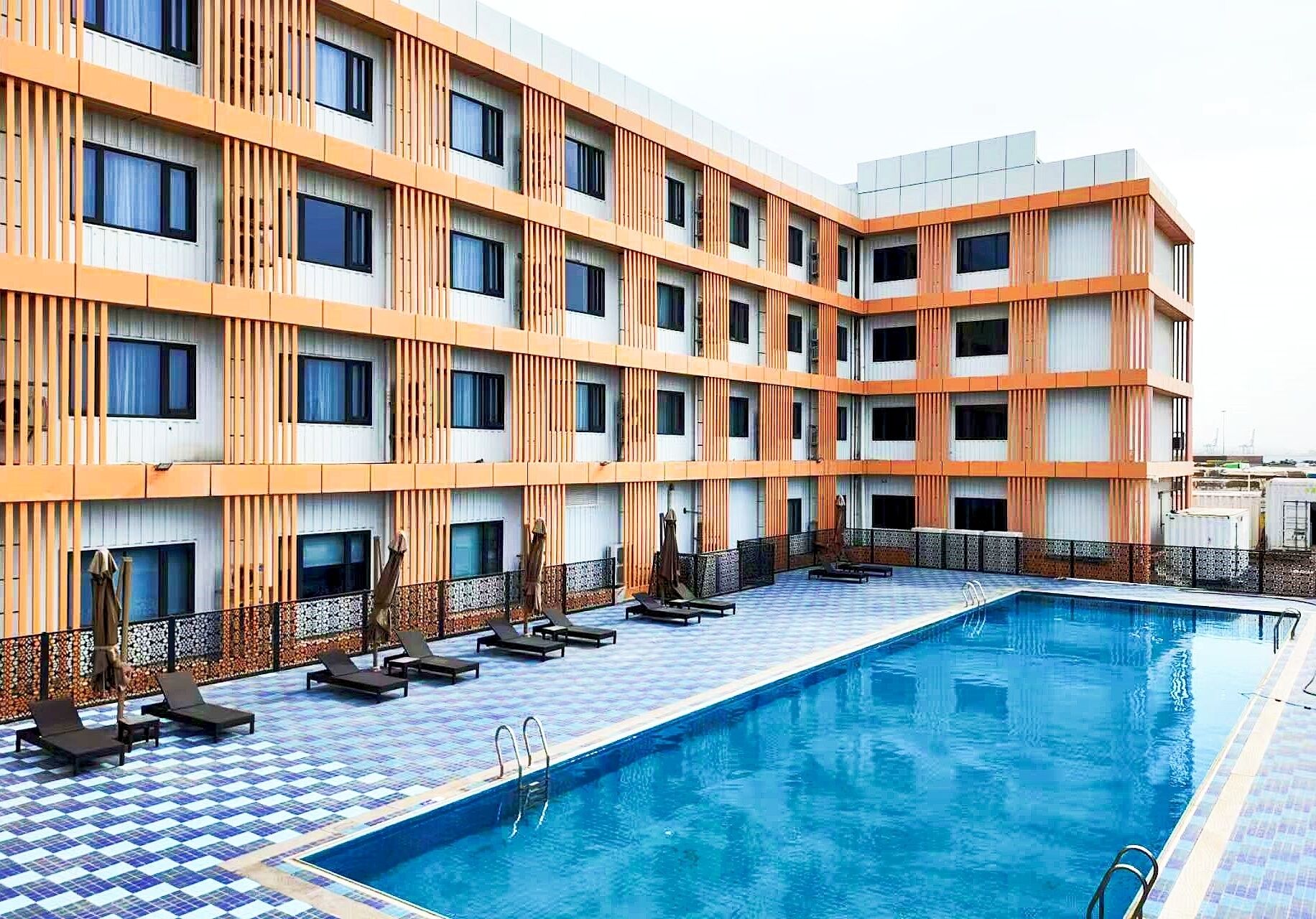 Un hotel con piscina, varios balcones y un diseño arquitectónico moderno.