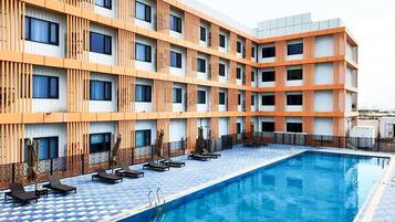 Un hotel con piscina, varios balcones y un diseño arquitectónico moderno.