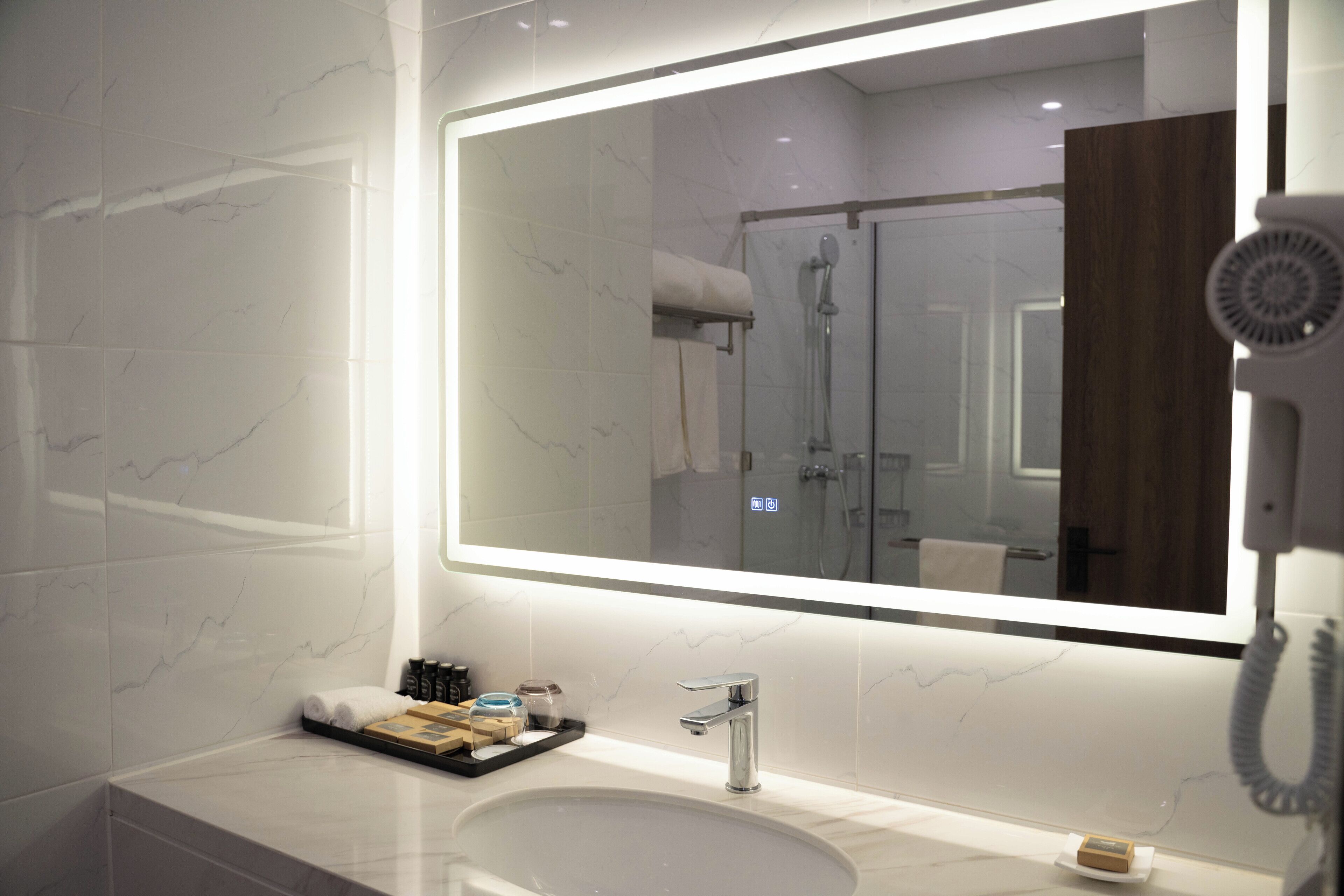 A modern bathroom with a large mirror, a sink, and a hairdryer.