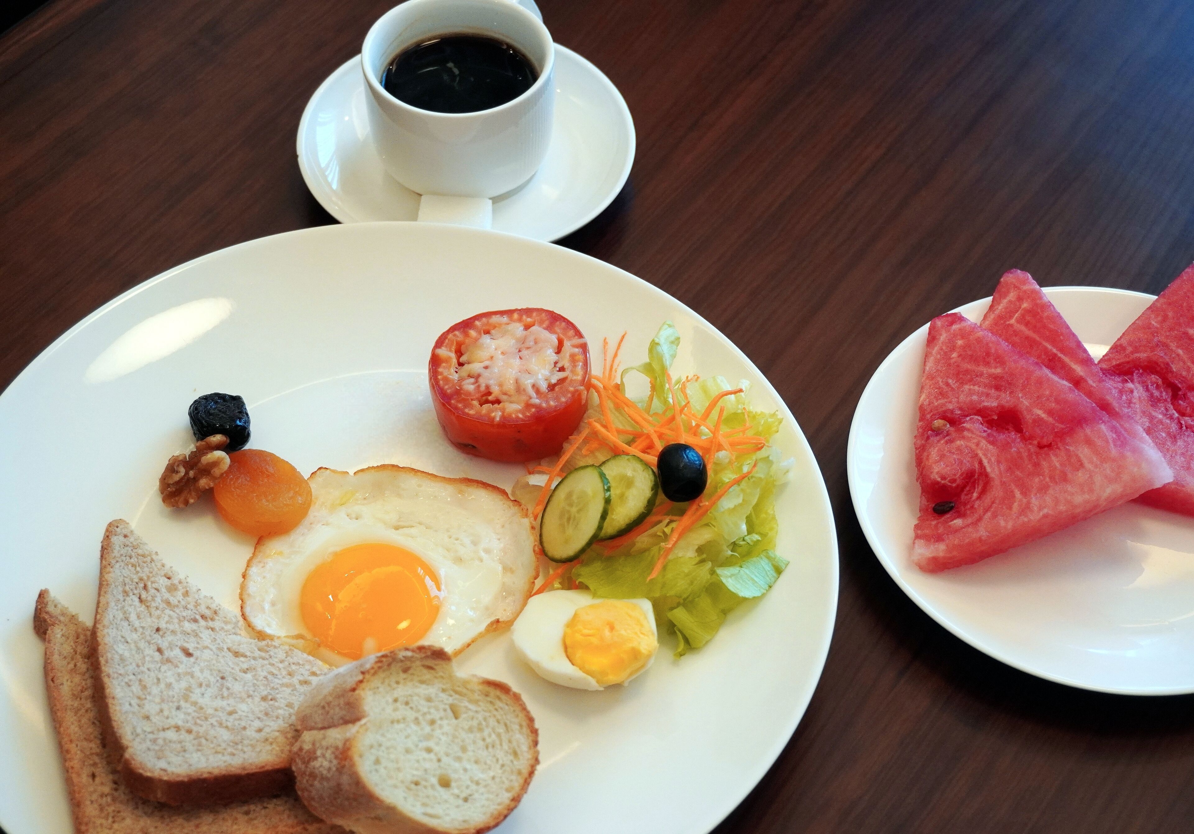 A breakfast plate with toast, a fried egg, a boiled egg, a tomato, cucumber slices, and a salad.