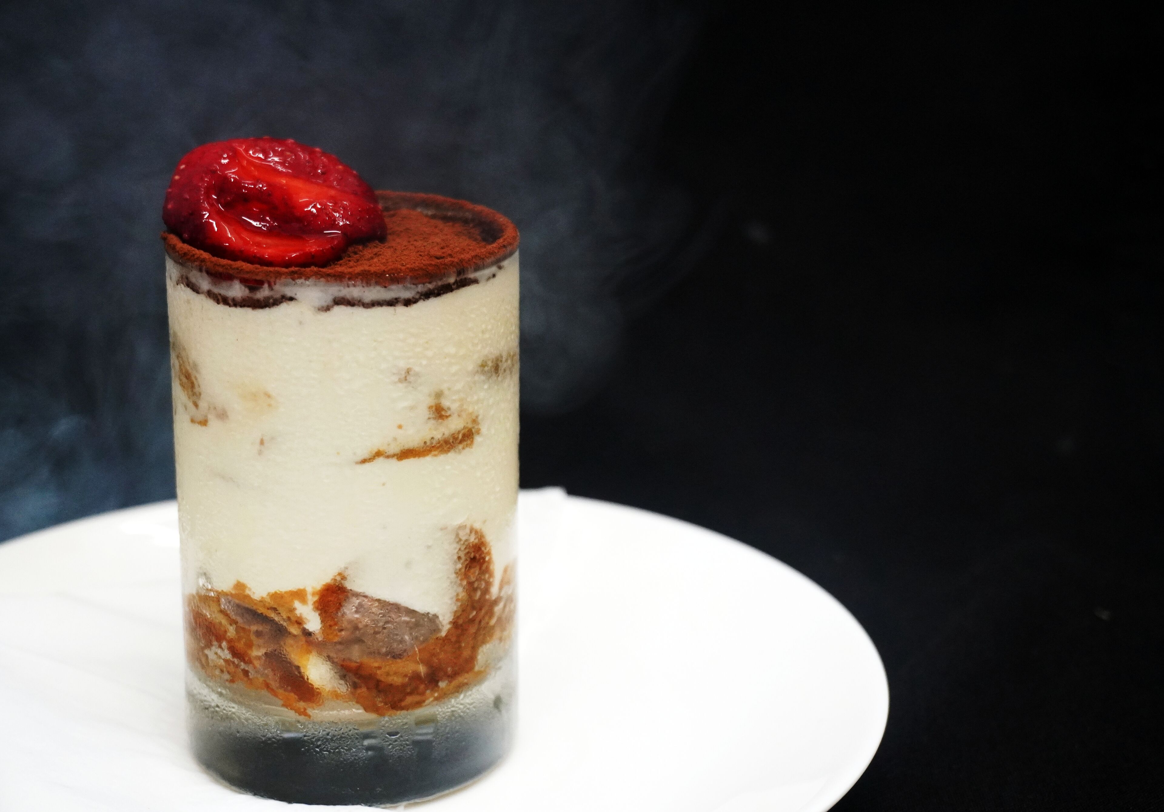 Ein Dessert mit Schichten und einer Kirsche obenauf.