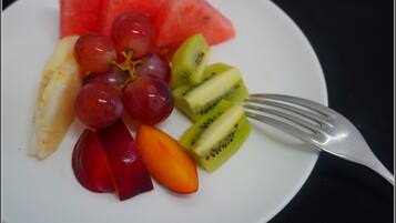 Un plato con varias frutas, incluyendo sandía, uvas, kiwi, melocotón y una naranja.