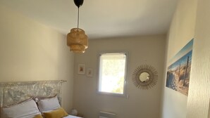 Une chambre à coucher avec un lit, une fenêtre, un élément de décoration murale et un ventilateur de plafond.