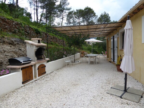 An outdoor patio with a barbecue grill, a pergola, outdoor seating, and a potted plant.
