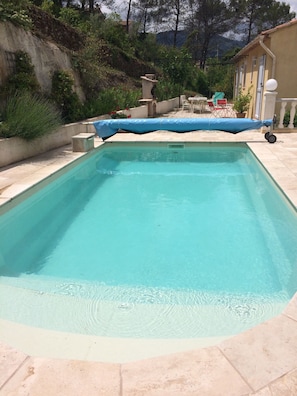 A rectangular swimming pool with clear water, surrounded by a tiled deck.