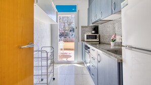 A compact kitchen with a microwave, oven, and coffee maker. - CANT DELS OCELLS 19 Roses (Rosas / Roses)