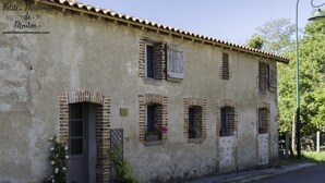 A rustic building with a weathered facade, multiple windows with shutters, and a small entrance door. - Renovated barn,  great for countryside walks, and bike rides (Azat-le-Ris)