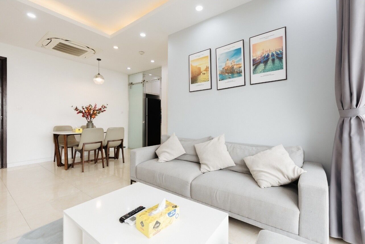 A modern living room with a sofa, a coffee table, and a dining area with chairs and a table.