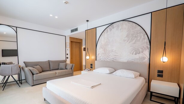 A modern bedroom with a large bed, a sofa, and a desk area.