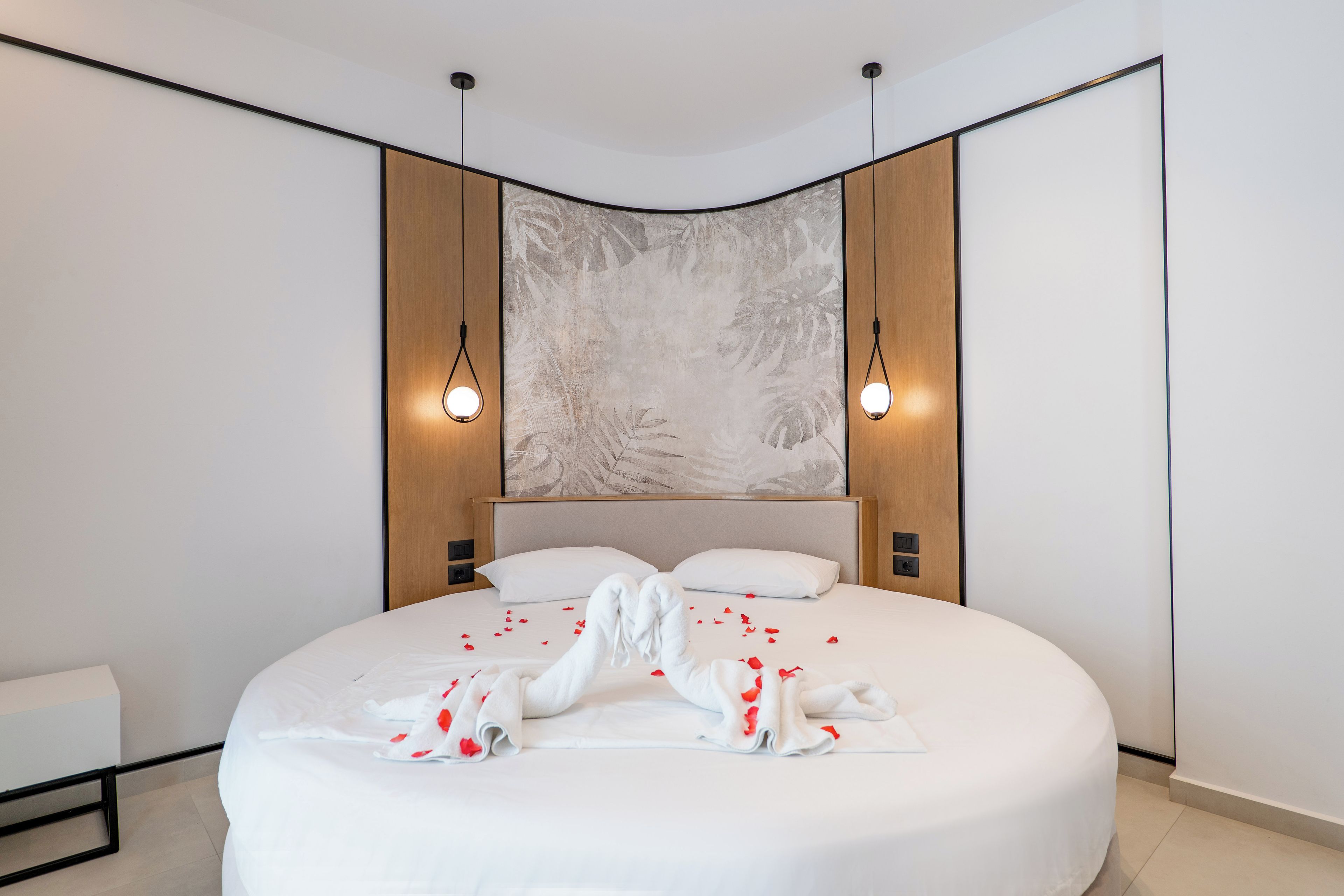 A modern bedroom with a large bed, two bedside lamps, and a decorative wall panel.