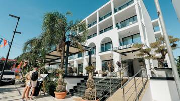 Um hotel moderno com fachada de vidro, área de estar externa e escadaria que leva à entrada.