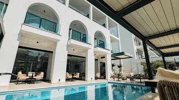 A modern hotel with a pool area, outdoor seating, and a covered patio.
